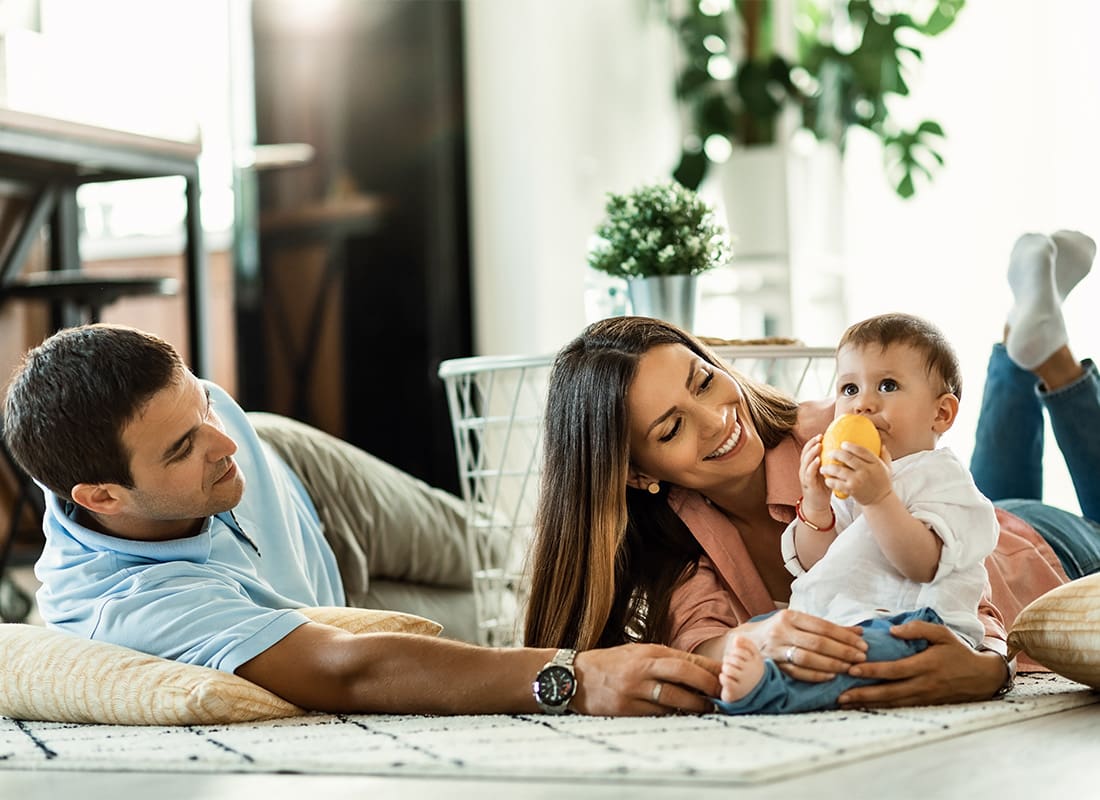 Personal Insurance - Portrait of Cheerful Parents Having Fun Playing with Their Baby in the Living Room